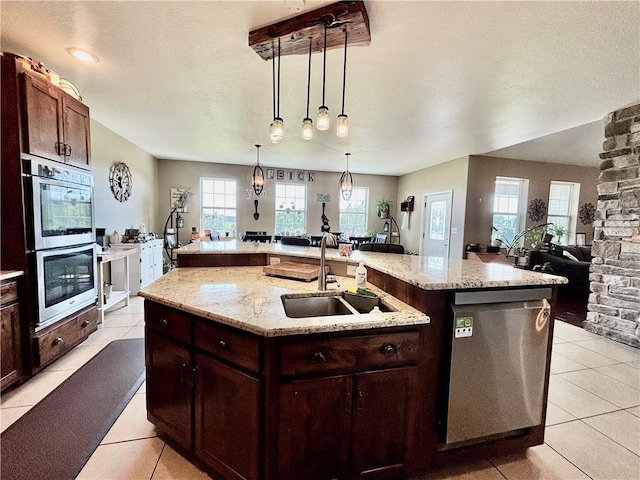 kitchen featuring light tile patterned flooring, appliances with stainless steel finishes, pendant lighting, an island with sink, and sink