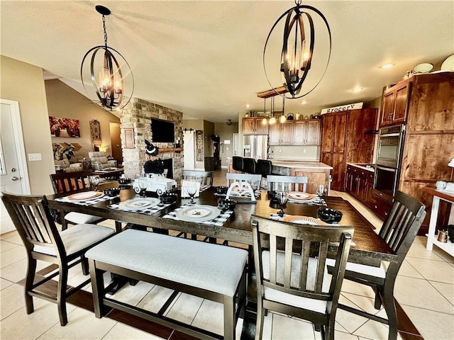 tiled dining room featuring an inviting chandelier, lofted ceiling, and a fireplace