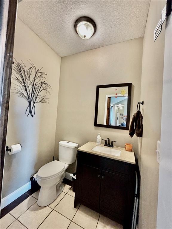 bathroom featuring vanity, a textured ceiling, tile patterned floors, and toilet