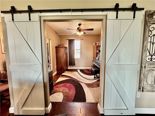 interior space featuring hardwood / wood-style flooring, a barn door, and ceiling fan