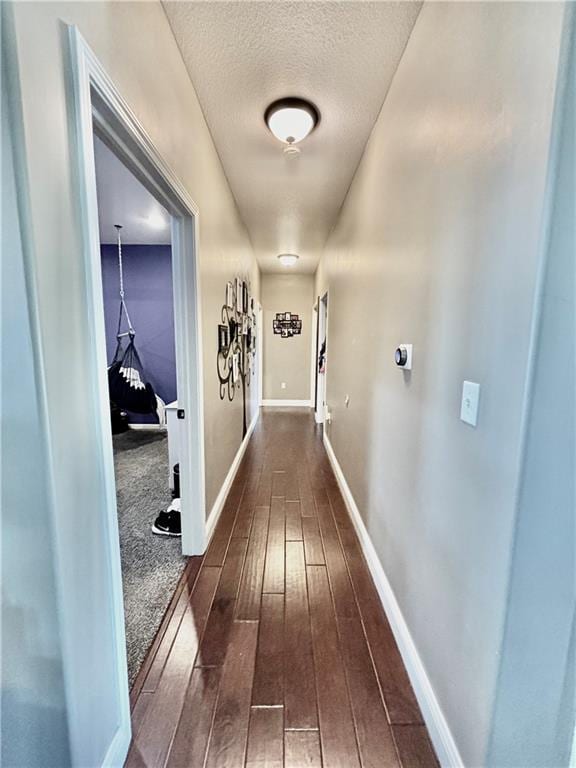 corridor with dark hardwood / wood-style floors and a textured ceiling