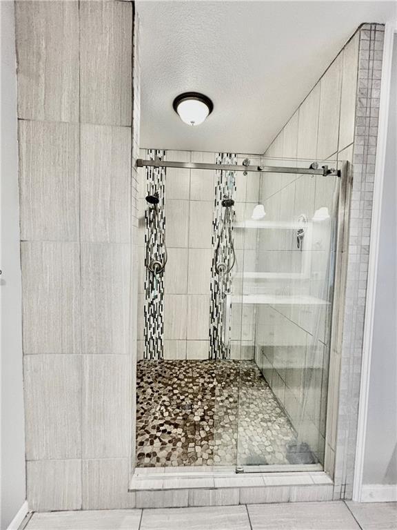 bathroom with an enclosed shower and a textured ceiling