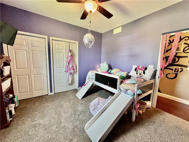 carpeted bedroom with two closets and ceiling fan with notable chandelier