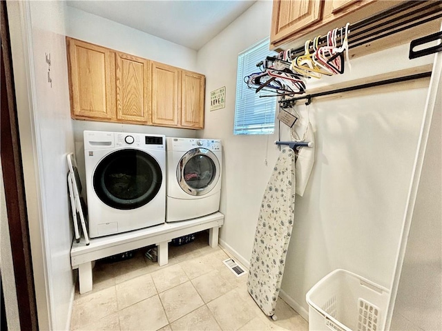 washroom with cabinets, light tile patterned floors, and washing machine and clothes dryer