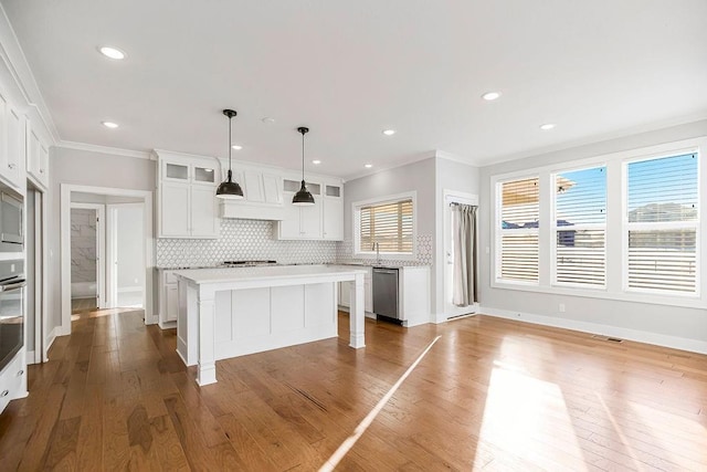 kitchen with a wealth of natural light, decorative backsplash, a center island, stainless steel appliances, and glass insert cabinets