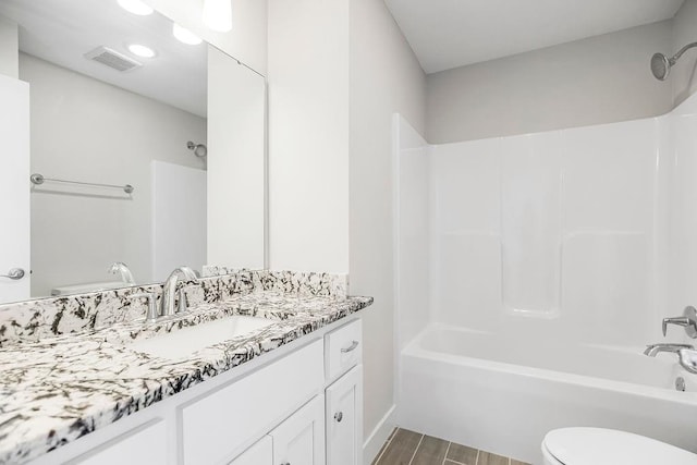 full bathroom featuring visible vents, shower / washtub combination, toilet, wood finished floors, and vanity