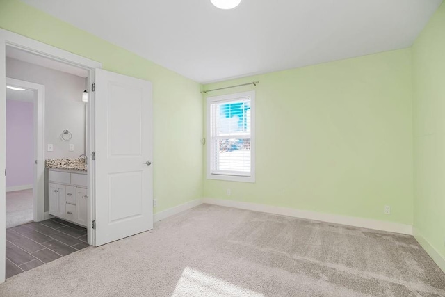 unfurnished bedroom with a sink, baseboards, and carpet floors