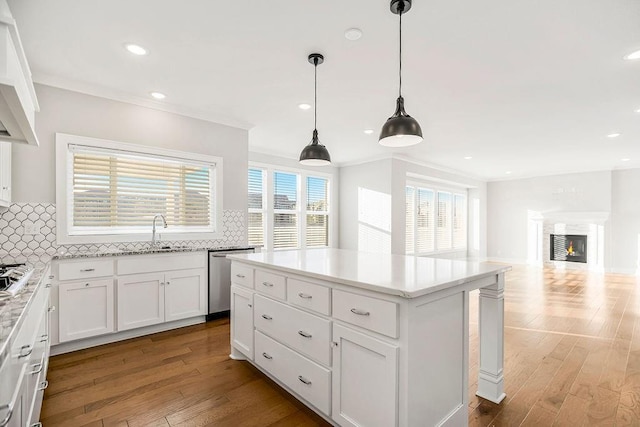 kitchen with dishwasher, a glass covered fireplace, tasteful backsplash, and a sink