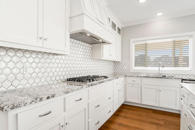 kitchen with stainless steel gas cooktop, a sink, decorative backsplash, and premium range hood