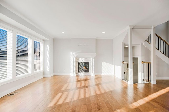 unfurnished living room with visible vents, baseboards, light wood-type flooring, recessed lighting, and a glass covered fireplace