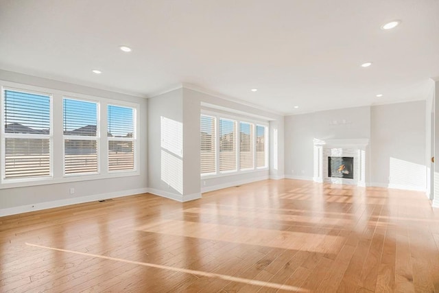 unfurnished living room with light wood finished floors, a glass covered fireplace, and baseboards