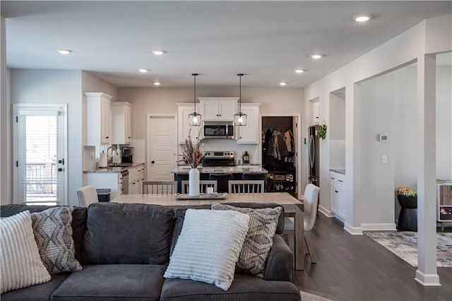 kitchen with appliances with stainless steel finishes, dark hardwood / wood-style flooring, sink, white cabinets, and hanging light fixtures