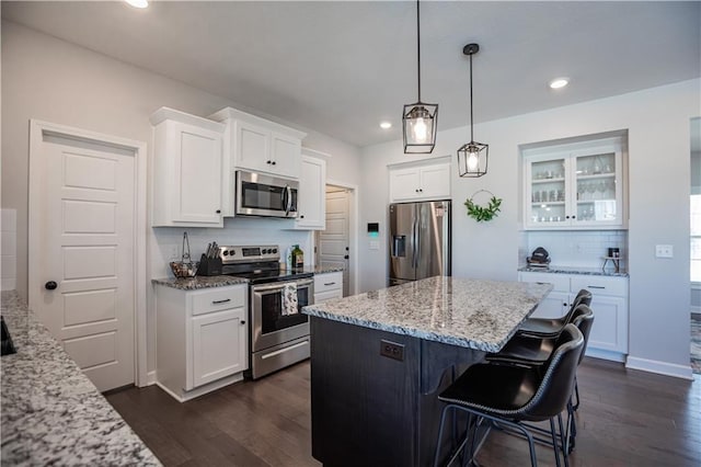 kitchen with light stone countertops, backsplash, a breakfast bar, stainless steel appliances, and white cabinets