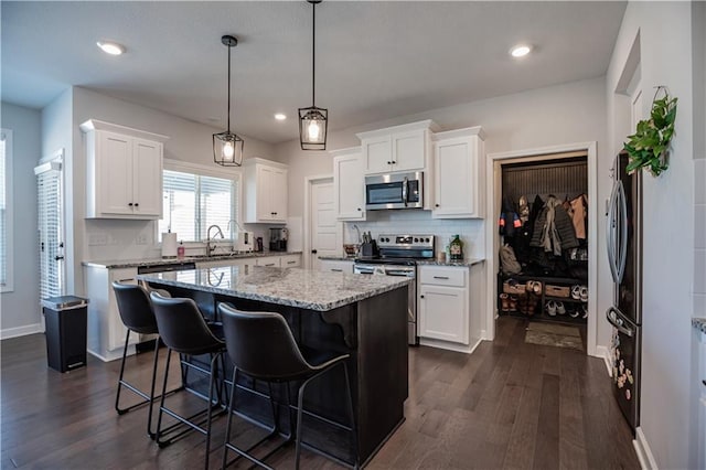 kitchen featuring white cabinets, decorative light fixtures, a kitchen island, and stainless steel appliances