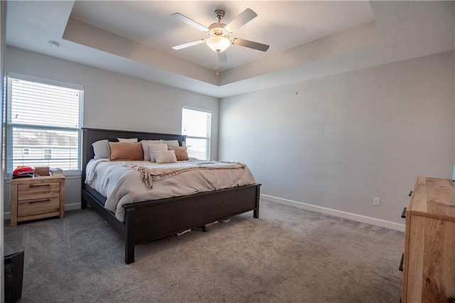 bedroom with multiple windows, a tray ceiling, and ceiling fan