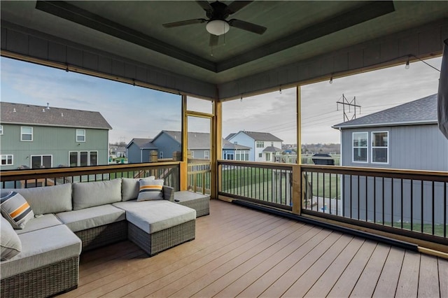 sunroom / solarium featuring plenty of natural light, ceiling fan, and a raised ceiling