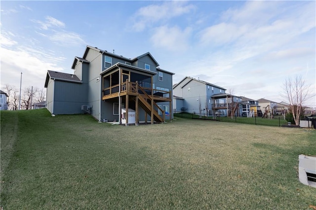 rear view of house with a sunroom, a wooden deck, and a lawn