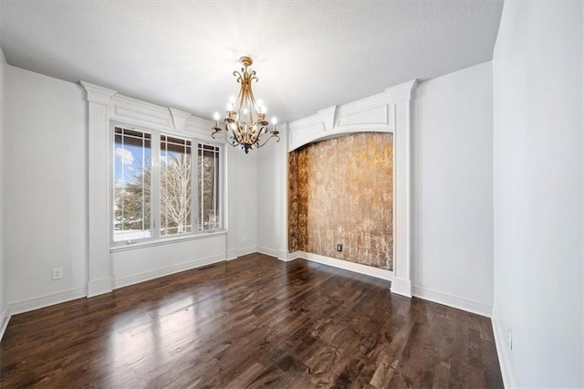 unfurnished dining area with baseboards, a chandelier, and dark wood-style flooring