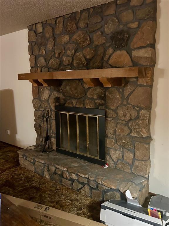 interior details featuring a fireplace, a textured ceiling, and wood finished floors