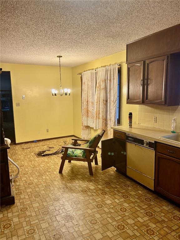 kitchen with dishwashing machine, backsplash, hanging light fixtures, light countertops, and a notable chandelier