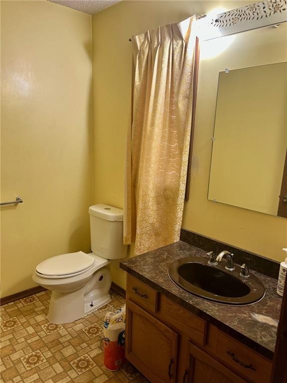 bathroom with a textured ceiling, vanity, toilet, and baseboards