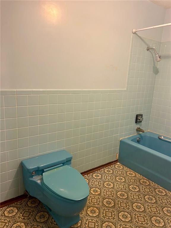 bathroom with washtub / shower combination, tile walls, toilet, and tile patterned floors