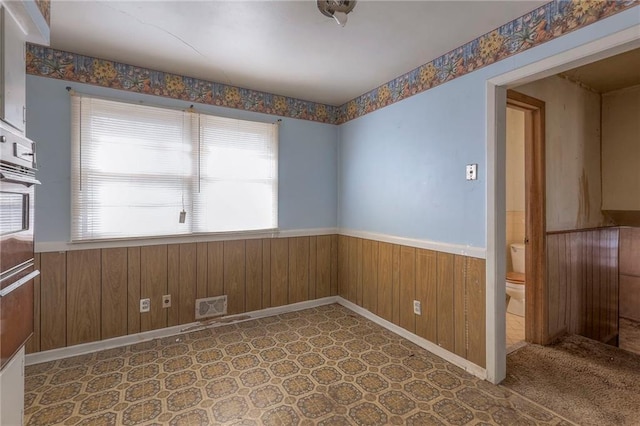 spare room featuring a wealth of natural light and wood walls