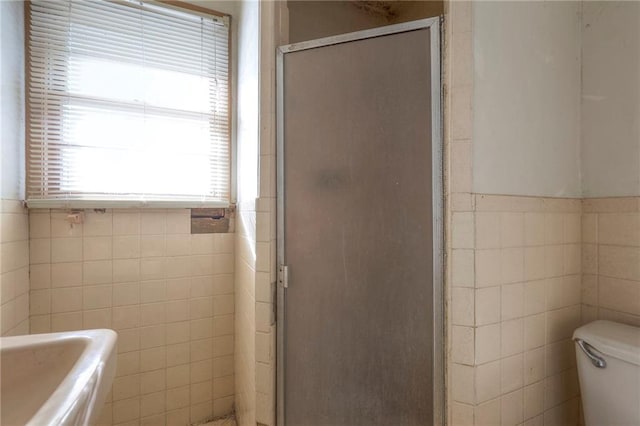 bathroom featuring toilet, an enclosed shower, and tile walls