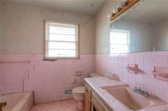 bathroom featuring vanity, tile walls, tile patterned flooring, toilet, and a bathing tub