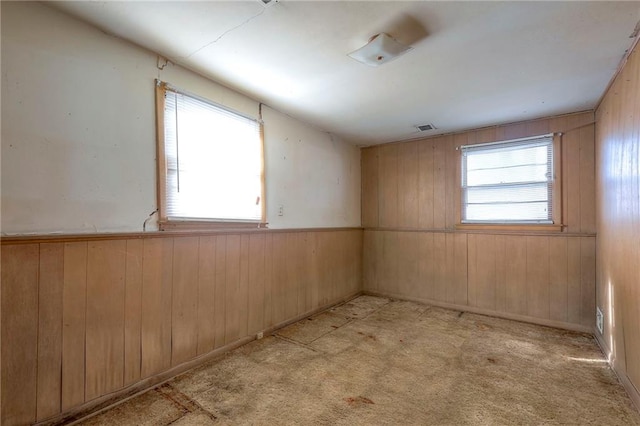 empty room featuring light carpet and wooden walls