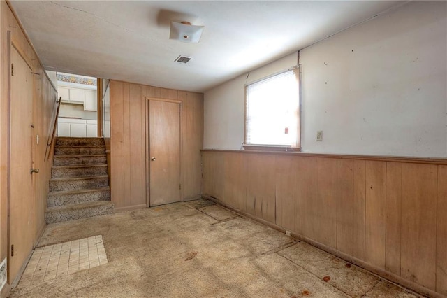 empty room with wooden walls and light colored carpet