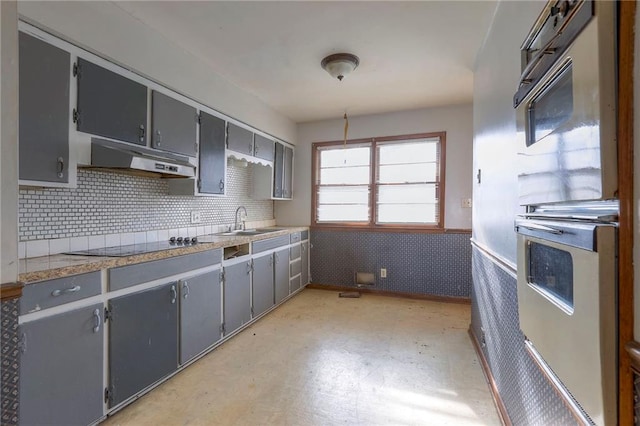 kitchen featuring black electric stovetop, gray cabinets, oven, and sink