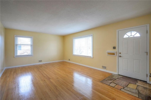 foyer entrance featuring light wood-style floors, visible vents, plenty of natural light, and a textured ceiling