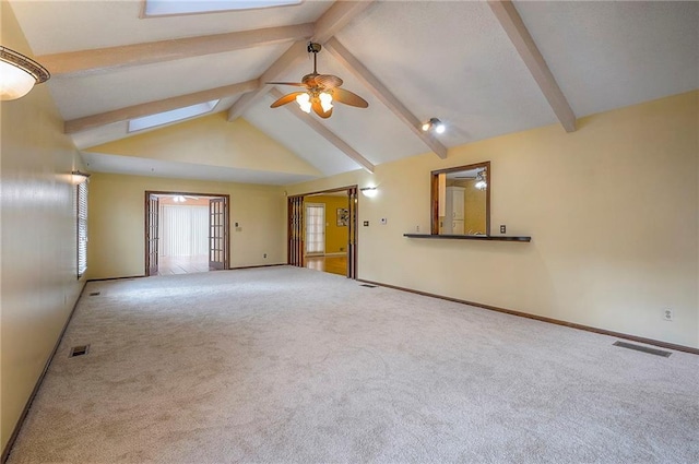 carpeted spare room featuring high vaulted ceiling, beamed ceiling, a skylight, and visible vents