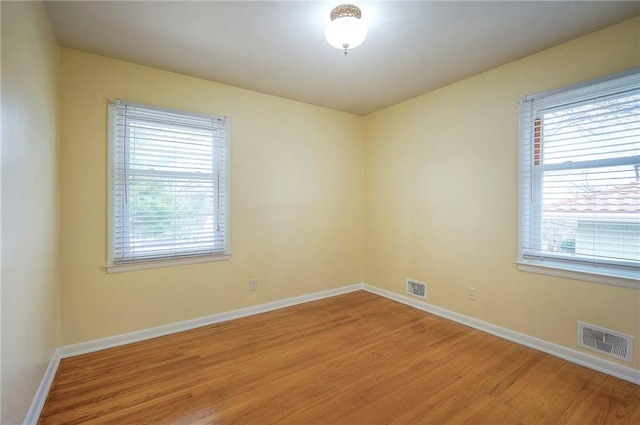 spare room featuring visible vents, light wood finished floors, and baseboards