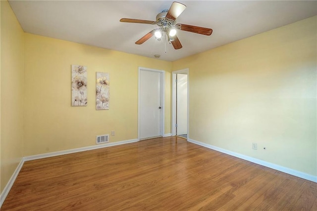 spare room featuring a ceiling fan, baseboards, visible vents, and wood finished floors