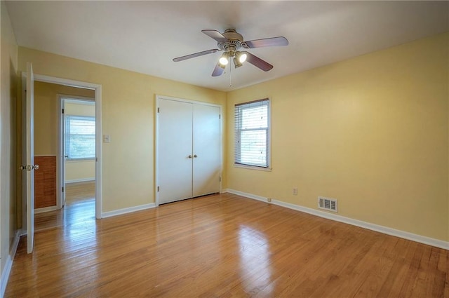 unfurnished bedroom featuring light wood finished floors, a closet, visible vents, ceiling fan, and baseboards