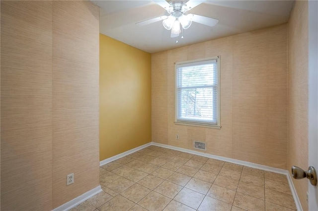 empty room with light tile patterned floors, baseboards, visible vents, and a ceiling fan