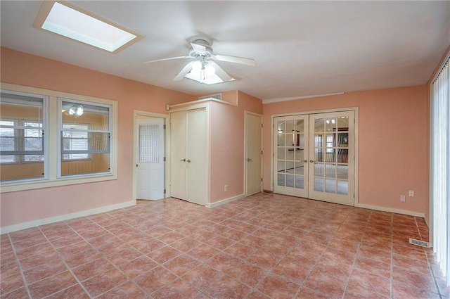 empty room with a skylight, baseboards, visible vents, and french doors