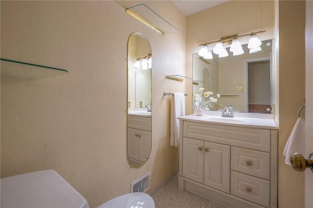 bathroom featuring toilet, vanity, visible vents, and tile patterned floors