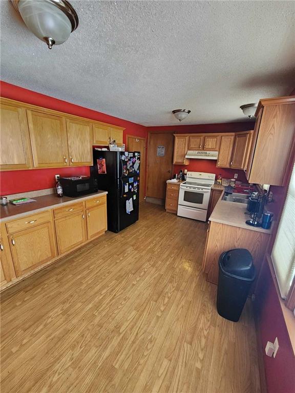 kitchen featuring black appliances, light hardwood / wood-style floors, sink, and a textured ceiling