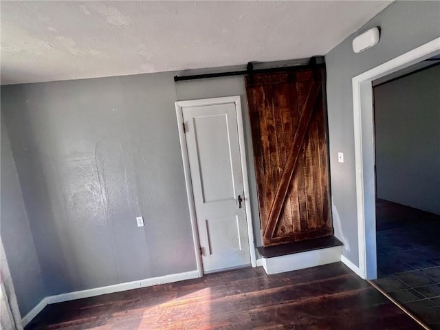 unfurnished room featuring a barn door and dark hardwood / wood-style floors