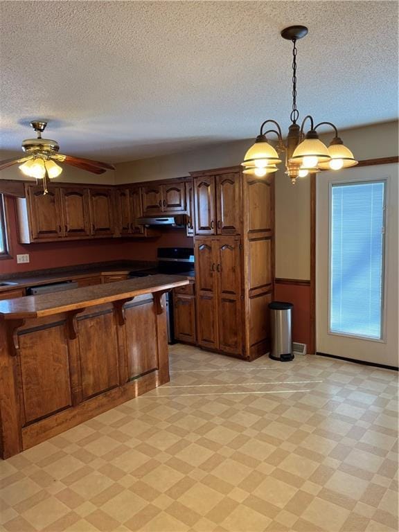 kitchen featuring a textured ceiling, pendant lighting, and ceiling fan with notable chandelier