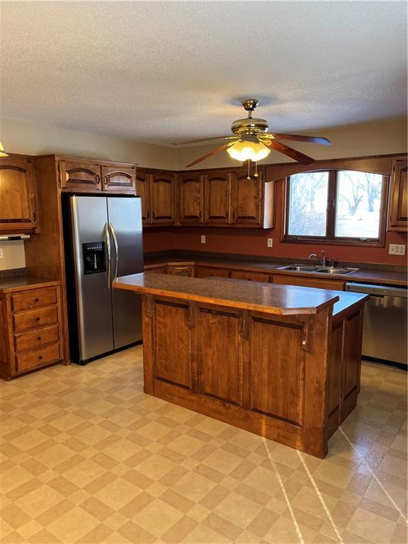 kitchen with sink, stainless steel appliances, a textured ceiling, and ceiling fan