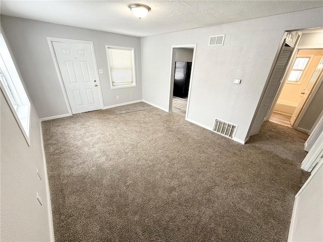 unfurnished bedroom with dark colored carpet, a textured ceiling, and a closet