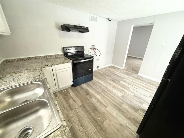 kitchen with white cabinets, sink, black electric range, light wood-type flooring, and light stone counters