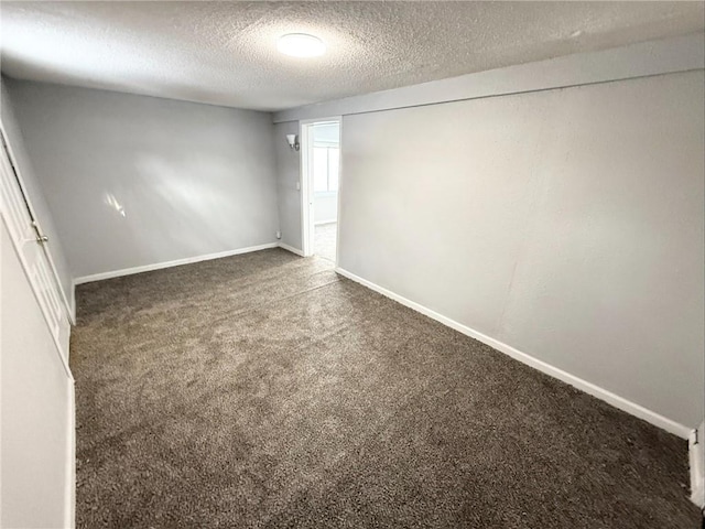 unfurnished room featuring dark colored carpet and a textured ceiling