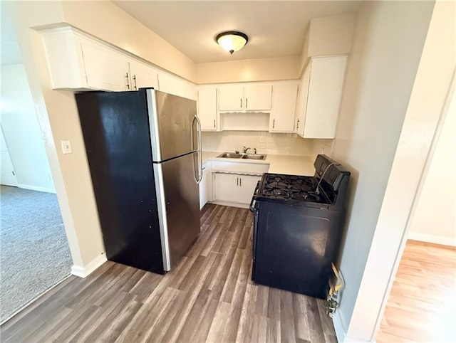 kitchen with white cabinets, stainless steel refrigerator, and black range with gas cooktop