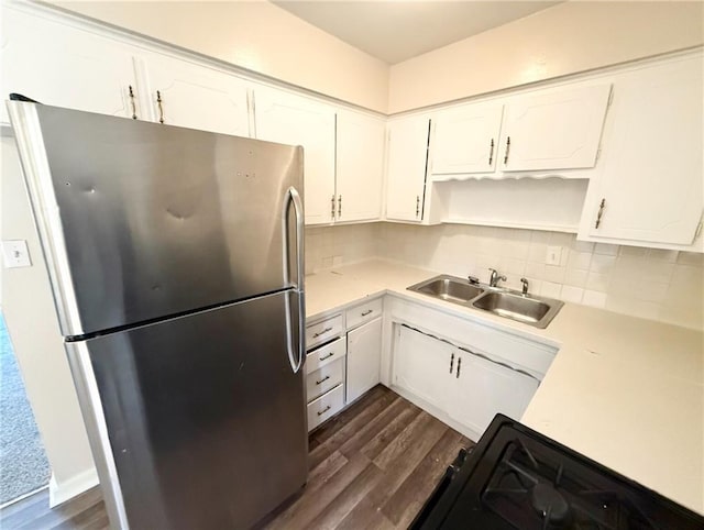 kitchen with stainless steel refrigerator, white cabinetry, sink, and range