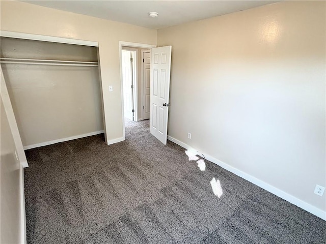 unfurnished bedroom with dark colored carpet and a closet